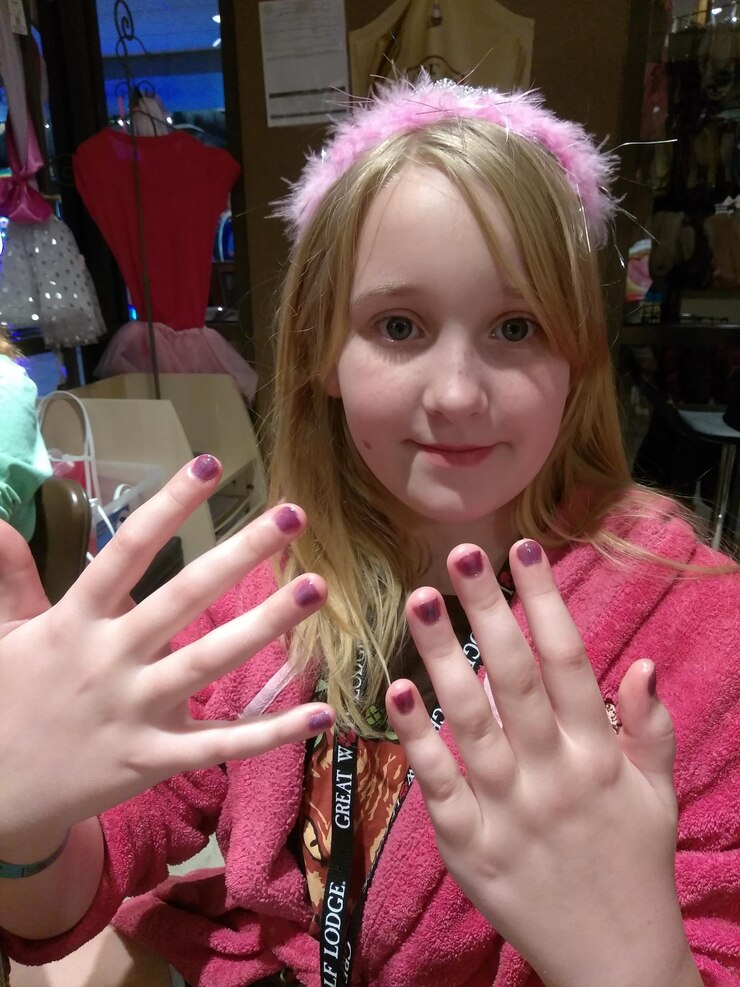 Photo portrait of cute girl showing purple nail polish