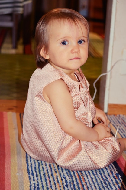 Photo portrait of cute girl sitting on bed at home