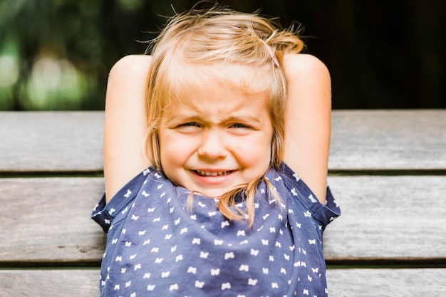 Photo portrait of cute girl sitting on bench outdoors