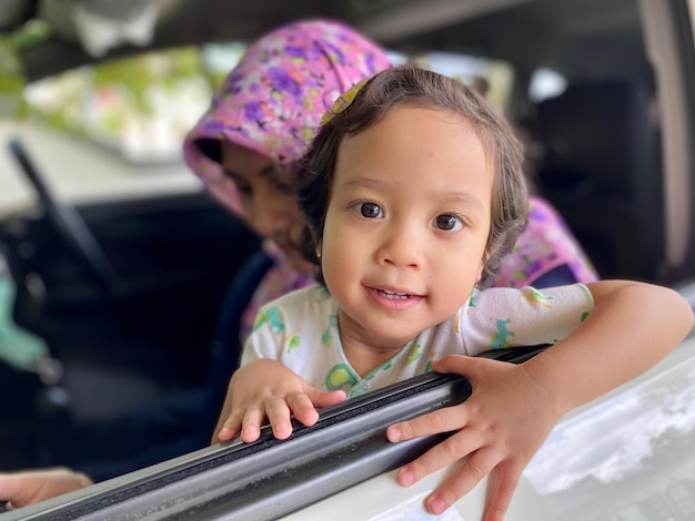 Photo portrait of cute girl sitting on car