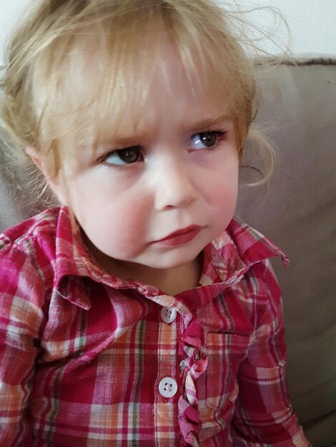 Photo portrait of cute girl sitting on sofa at home