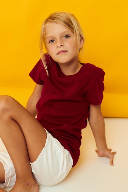 Photo portrait of cute girl sitting on yellow wall