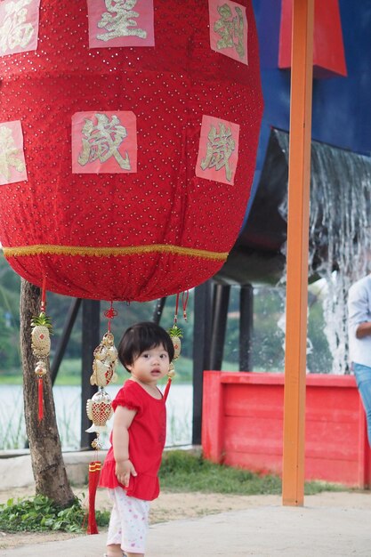 Portrait of cute girl standing against lantern