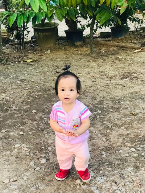 Portrait of cute girl standing against pink plants