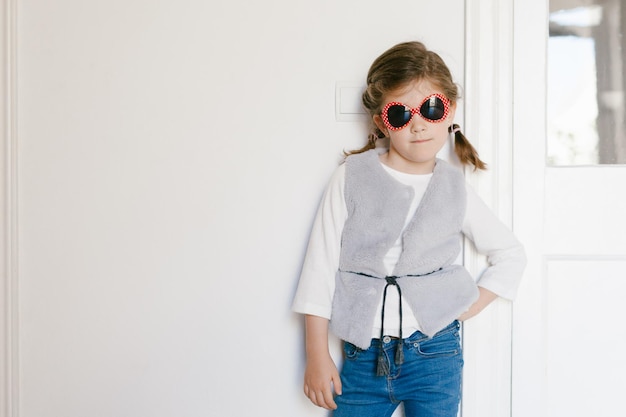 Portrait of cute girl standing against wall at home