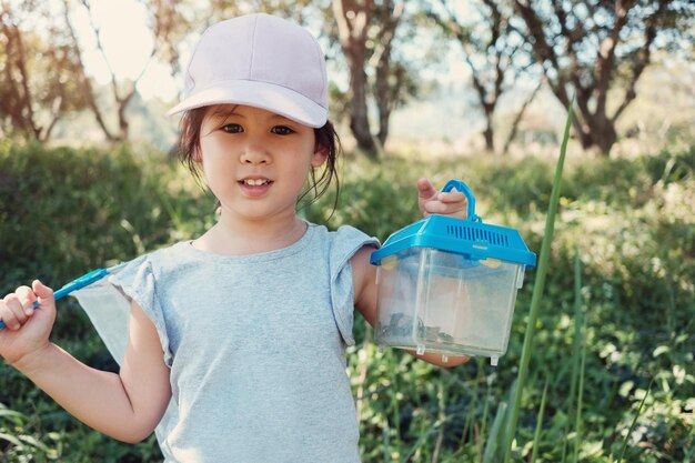 Photo portrait of cute girl standing with container on field