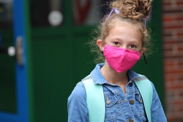 Foto ritratto di una ragazza carina che indossa una maschera antinfluenzale in piedi all'aperto