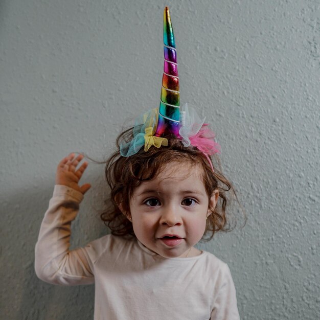 Photo portrait of cute girl wearing unicorn hat while standing against wall