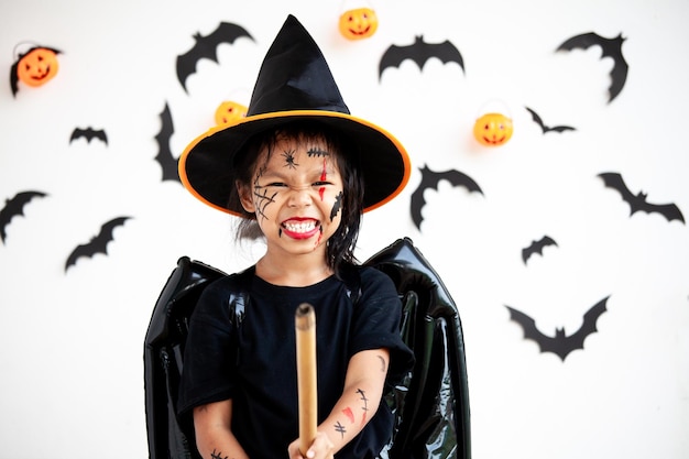 Photo portrait of cute girl wearing witch costume against wall