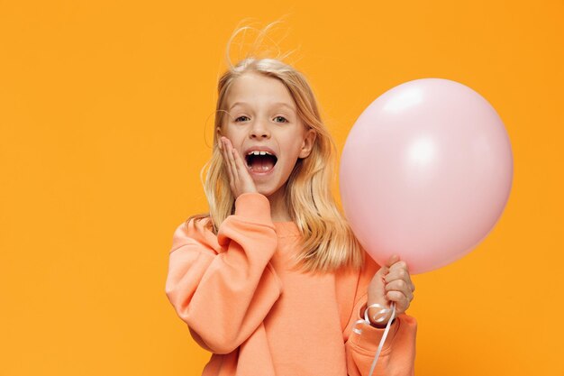 Portrait of cute girl with balloons against yellow background