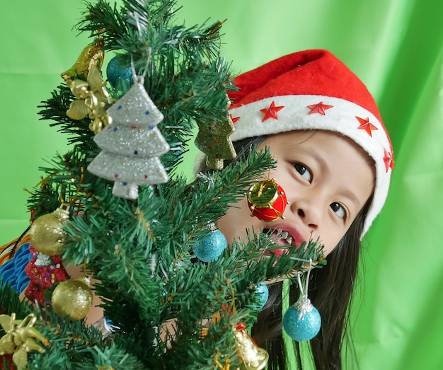 Photo portrait of cute girl with christmas tree against curtain