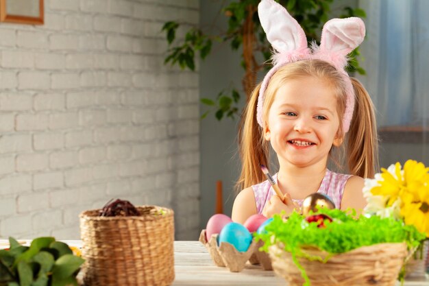 Portrait of a cute girl with paintbrush  ready to paint eggs