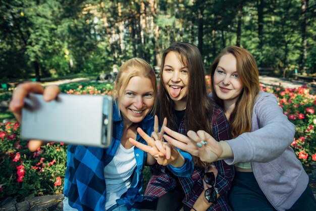 夏の公園でスマートフォンでselfieを取ってかわいいガールフレンドの肖像画