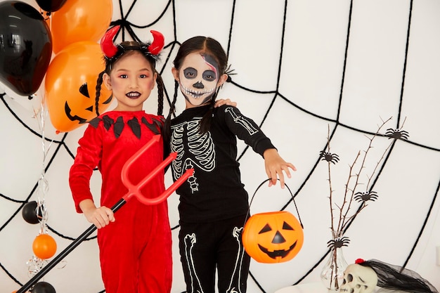 Photo portrait of cute girls wearing halloween costumes standing against wall