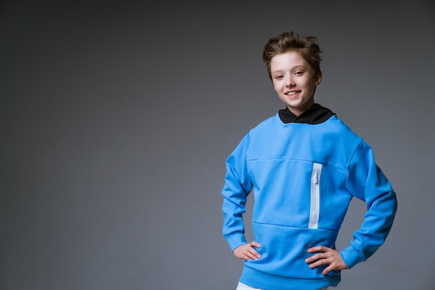 portrait of cute guy of european appearance with asnowwhite toothy smile in a blue sweatshirt pos