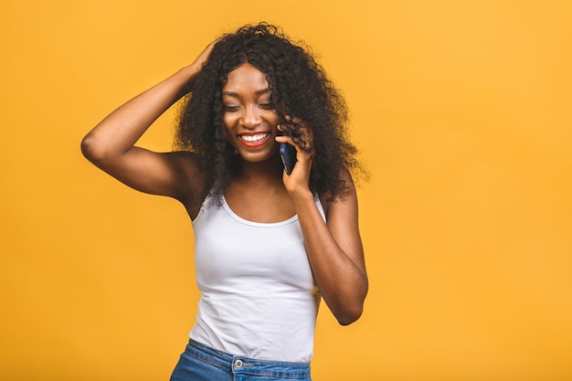 Ritratto di una ragazza nera afroamericana felice sveglia che parla sul telefono cellulare e che ride