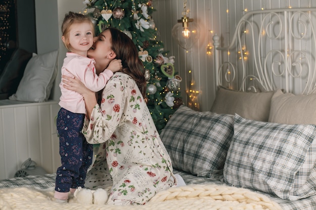 Portrait of cute happy family in pajamas on Christmas in bed