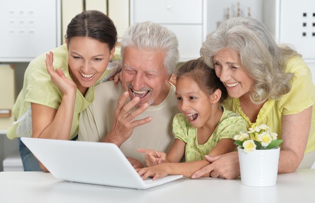 Portrait of cute happy family using laptop at home