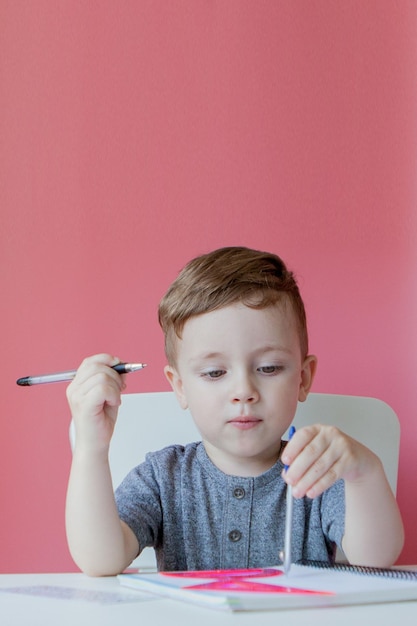 Portrait of cute kid boy at home making homework Little concentrated child writing with colorful pencil indoors Elementary school and education Kid learning writing letters and numbers