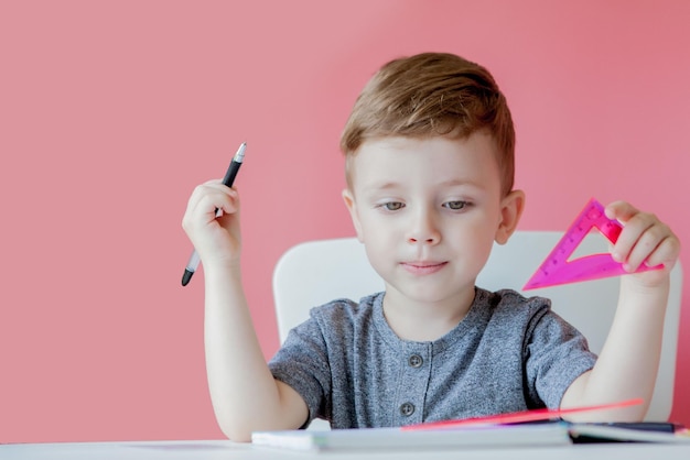 Ritratto di ragazzo carino a casa che fa i compiti piccolo bambino concentrato che scrive con una matita colorata all'interno scuola elementare e istruzione bambino che impara a scrivere lettere e numeri