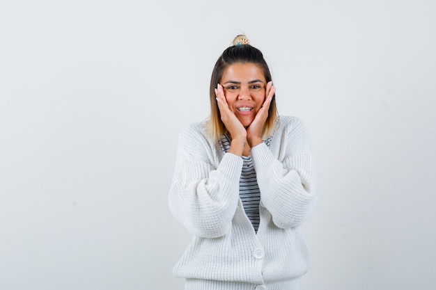 Portrait of cute lady pillowing face on her hands in t-shirt, cardigan and looking happy