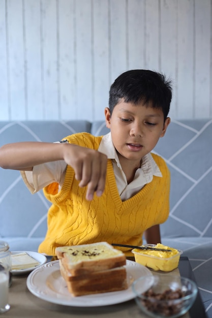 Portrait of cute little Asian kid preparing breakfast for himself before go to school