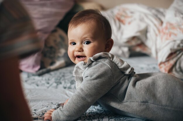 Photo portrait of cute little baby girl lying on stomach crawling smiling to camera smiling happy child