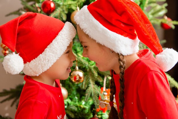 portrait of a cute little boy and girl in red pajamas on the background of a Christmas tree winter