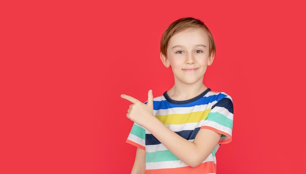 Portrait cute little boy with pointing to empty place on background surprised preschooler showing copy space for promotional ad Portrait joyful child pointing at free space for advertisement