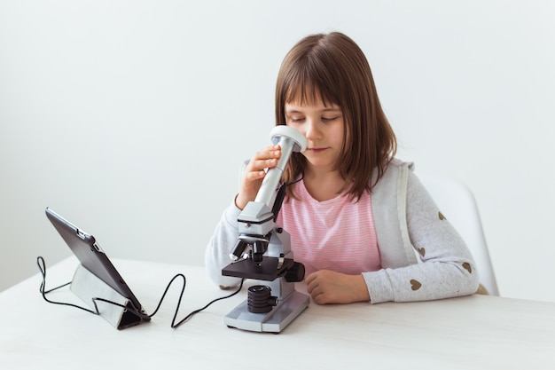 Portrait of cute little child doing homework with a digital microscope. Technologies, science and children concept.