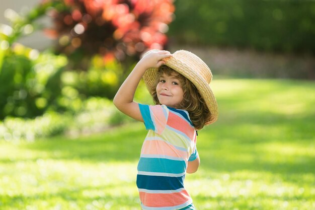 Portrait of a cute little child in straw hat in summer nature park Childhood and parenting concept