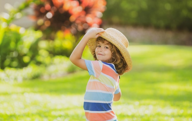 Portrait of a cute little child in straw hat in summer nature park Childhood and parenting concept