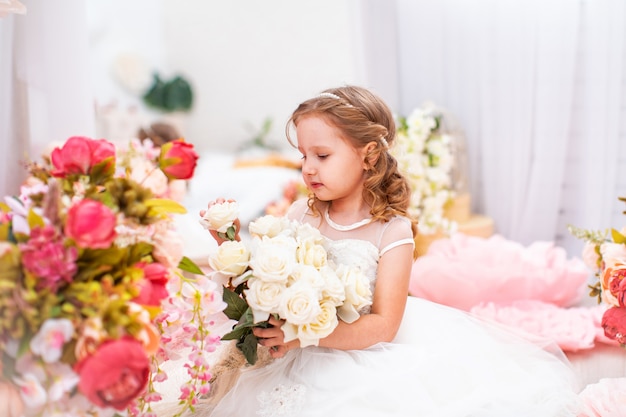 Portrait cute little girl in beautiful dress with wavy, with bouquet of roses.