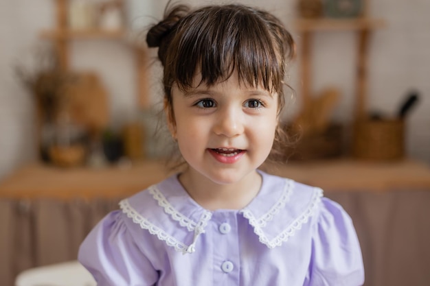 Photo portrait of a cute little girl in a lilac dress in the kitchen. card, space for text, banner