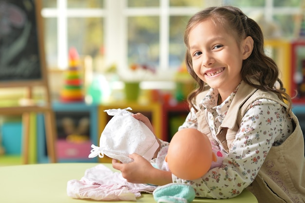 Photo portrait of a cute little girl playing with doll