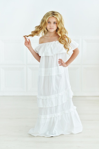 Photo portrait of cute little girl posing in white dress