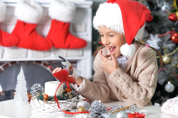 Portrait of cute little girl in Santa hat preparing for Christmas at home