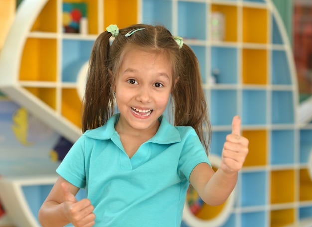 Photo portrait of a cute little girl showing thumbs up