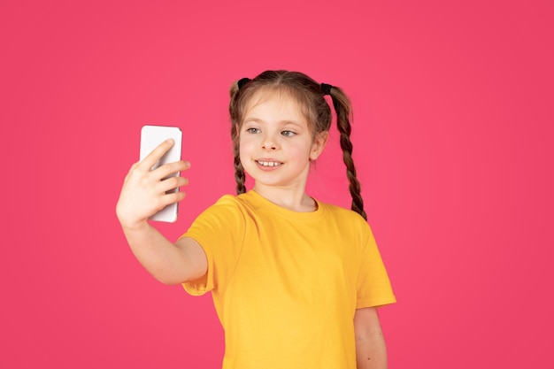 Портрет милой маленькой девочки, делающей селфи на смартфоне