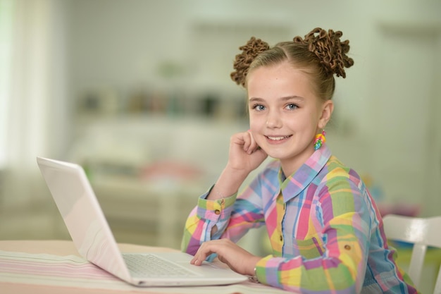 Portrait of cute little girl using laptop at her room