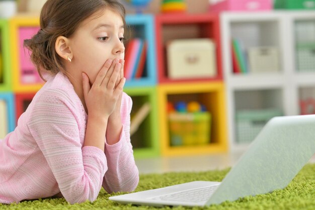 Portrait of cute little girl using modern laptop