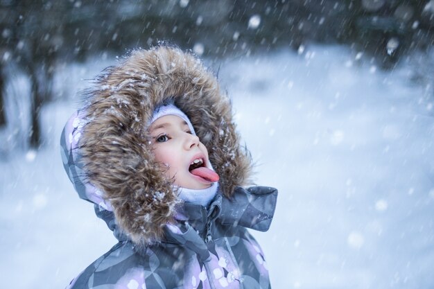 冬の日に口で雪をキャッチするかわいい女の子の肖像画