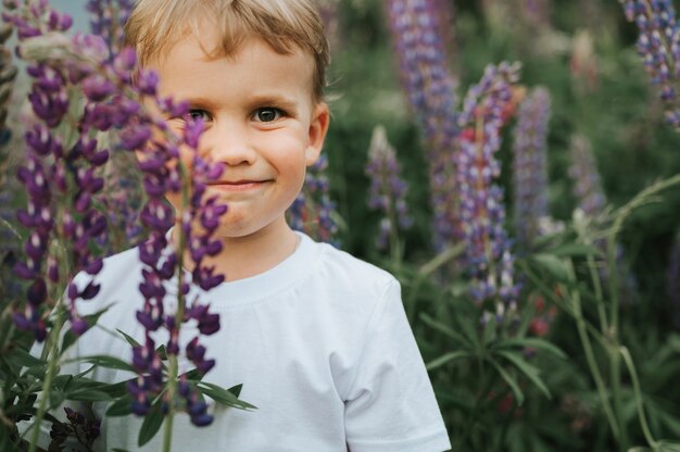 Portrait of a cute little happy boy with bloom lupines