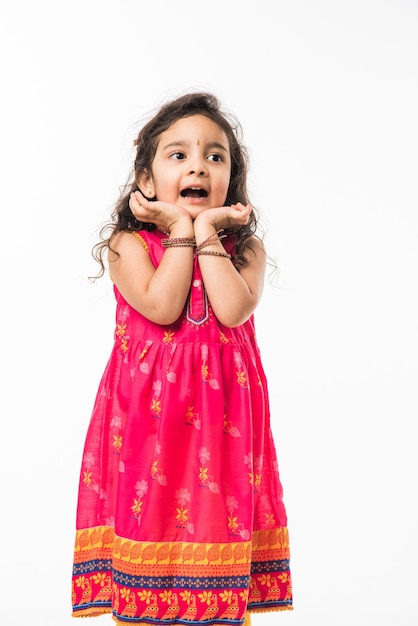 Portrait of cute little Indian girl model, sitting isolated over white background