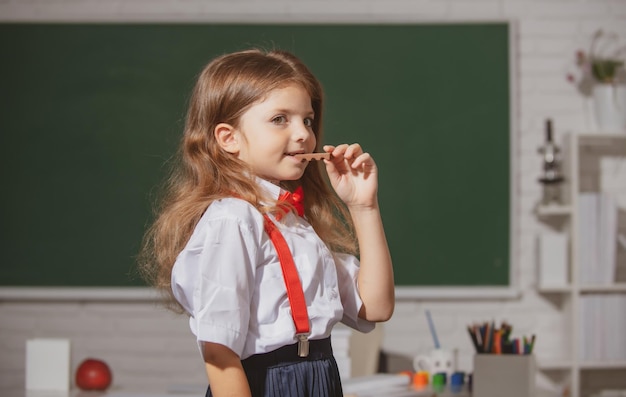 小学校と初等教育の教室でチョコレートを食べる制服を着たかわいい素敵な女の子の肖像画