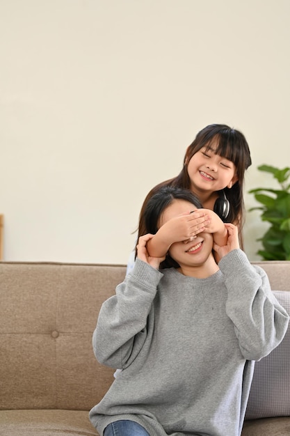 Portrait Cute and playful young Asian girl surprising or playing peek a boo with her mom