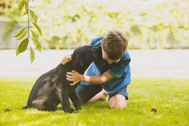 키스하고 주인을 핥는 귀여운 강아지의 초상화 어린 소년 강아지와 아이 사이의 진정한 사랑과 감탄의 감정 강아지를 키우는 소년의 꿈이 이루어졌습니다