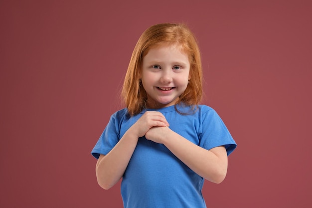 Portrait of cute redhead emotional little girl on red background