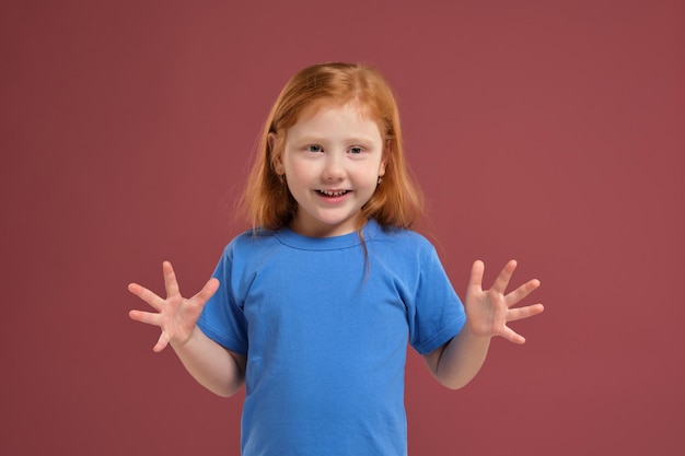 Portrait of cute redhead emotional little girl on red background