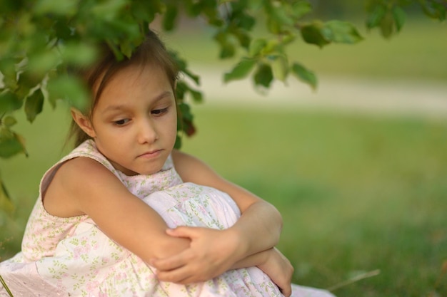 Portrait of cute sad little girl in park